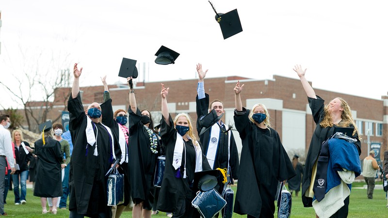 College graduages throw their hats into the air.