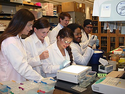 Califorina Aggie alums and teen scientists in a USU lab