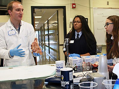 USU biology major James Rohwer talking with high school students in a USU lab