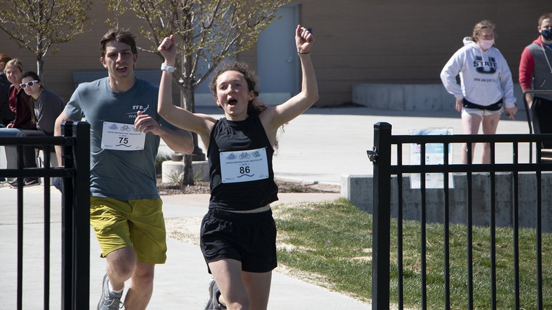 Two people in athletic wear run through a gate.