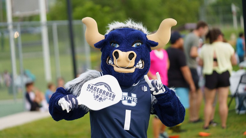 Utah State mascot Big Blue holding a pickleball paddle.