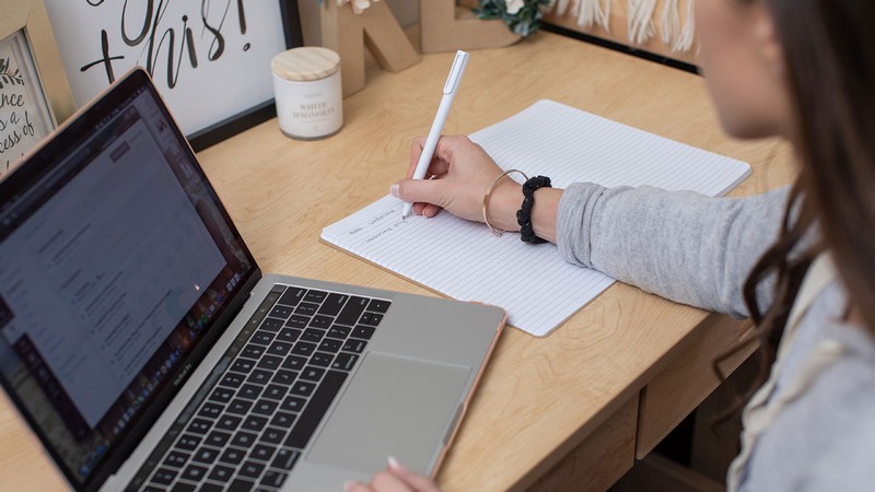 person studying on a desk with an open laptop.