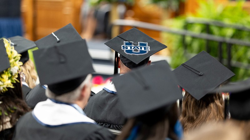 Utah State graduates in caps and gowns at commencement.