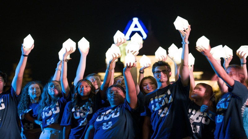 People holding A-shaped lanterns up in front of Old Main.