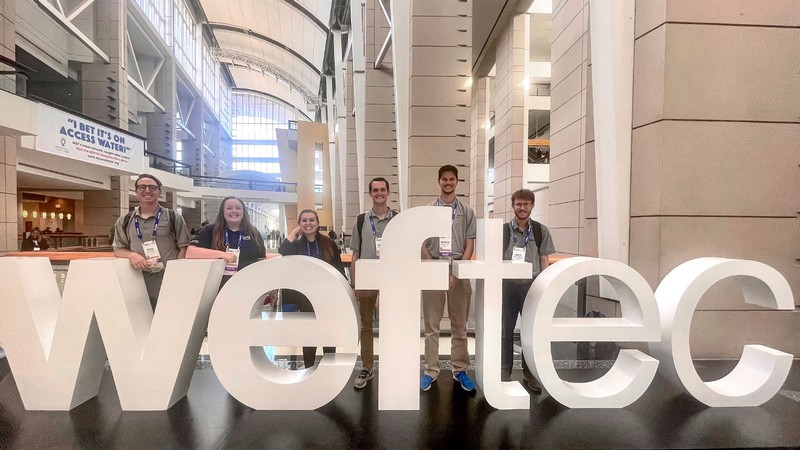 USU Engineering students stand behind sign that reads weftec