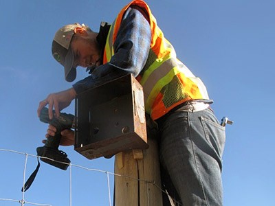 USU graduate student Joe Flower checking a camera at a wildlife crossing