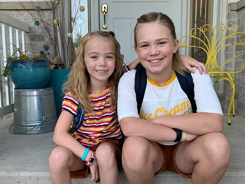 two girls on a porch on the first day of school