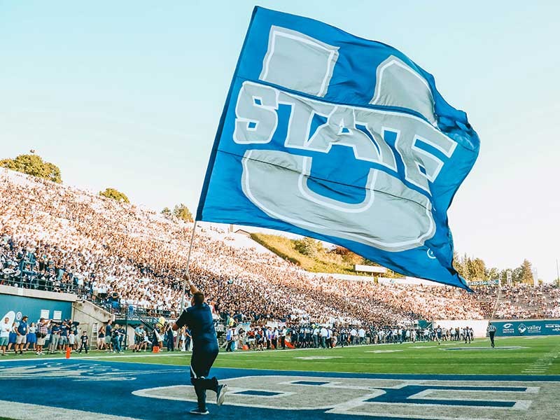 Aggie football player running with the U State flag