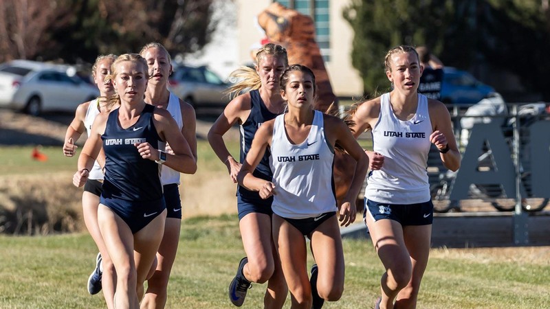 USU women athletes run on a field.