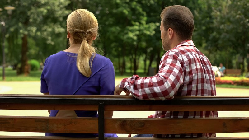 A couple sits on a park bench.