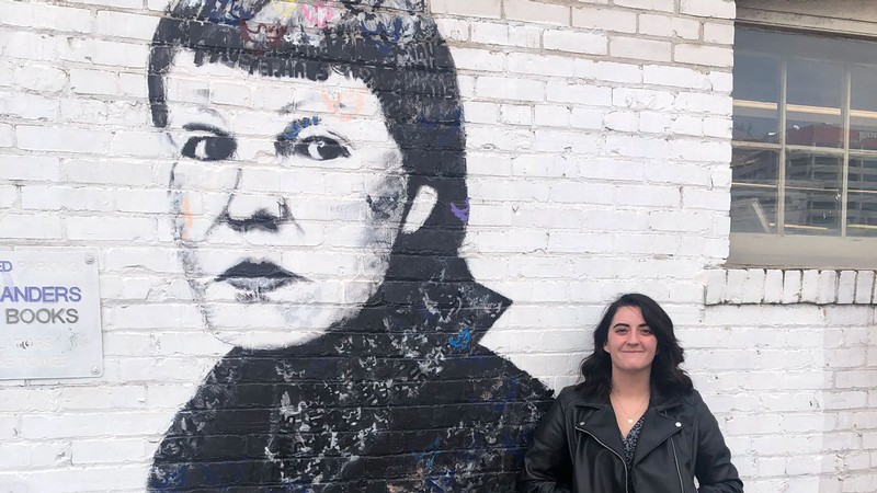 Tegan Durfee next to wall art of USU alumna May Swenson.