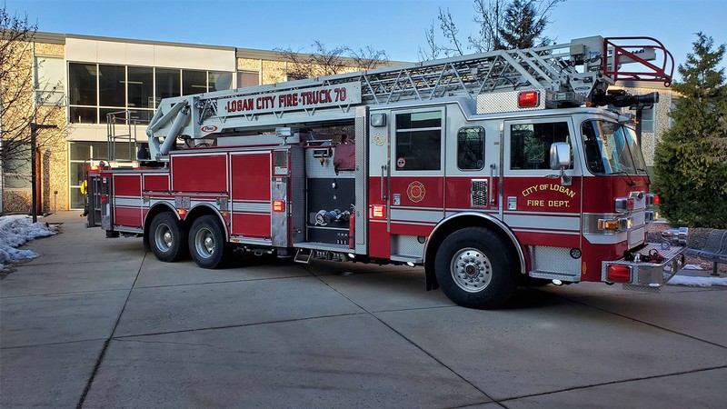 A Logan City Fire Department ladder truck parks on the sidewalk on the USU Logan campus.