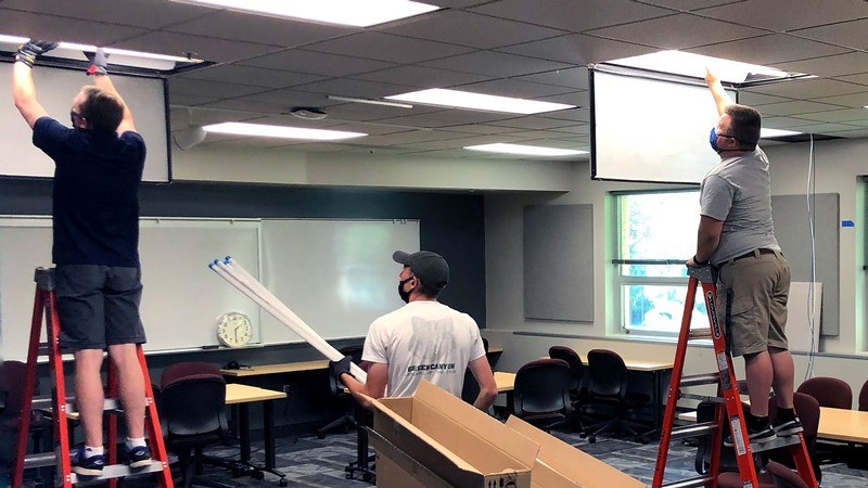 USU facilities employees install lights in a classroom.