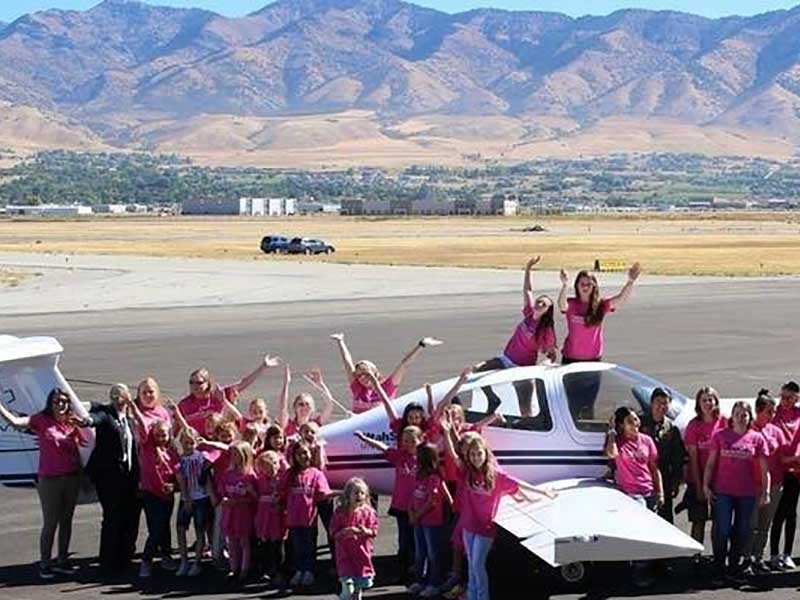 girls surrounding a USU plane