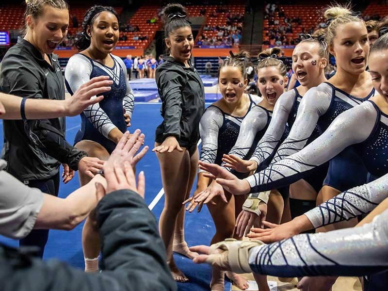 women's gymnastics team cheering in a huddle