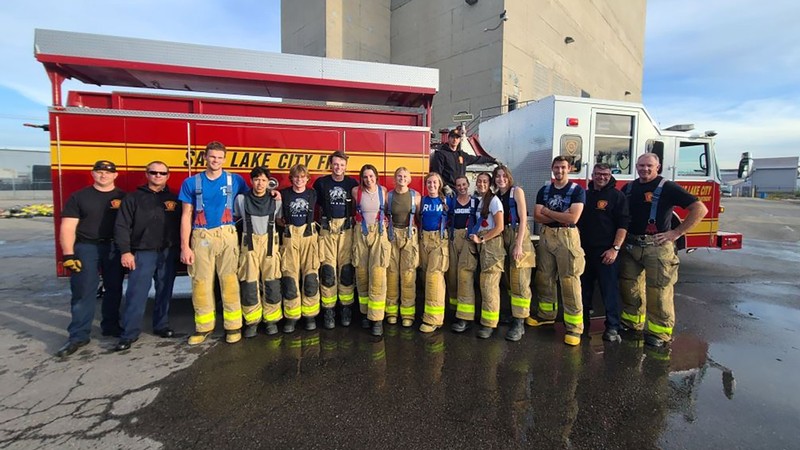 USU track and field sprinters and hurdlers gather for a photo in front of a fire truck.