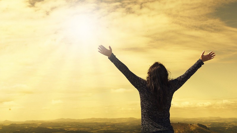 Person holding their hands up to a beautiful sunset.