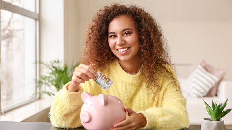 woman putting money into a piggybank.