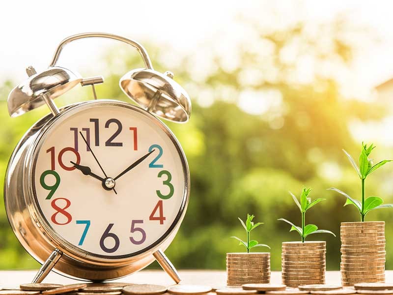 clock with growing plants in three different phases