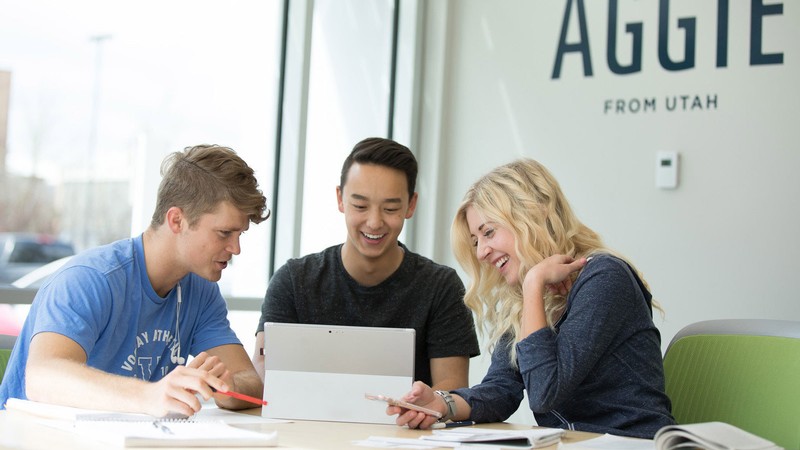 three students gathered around a computer.