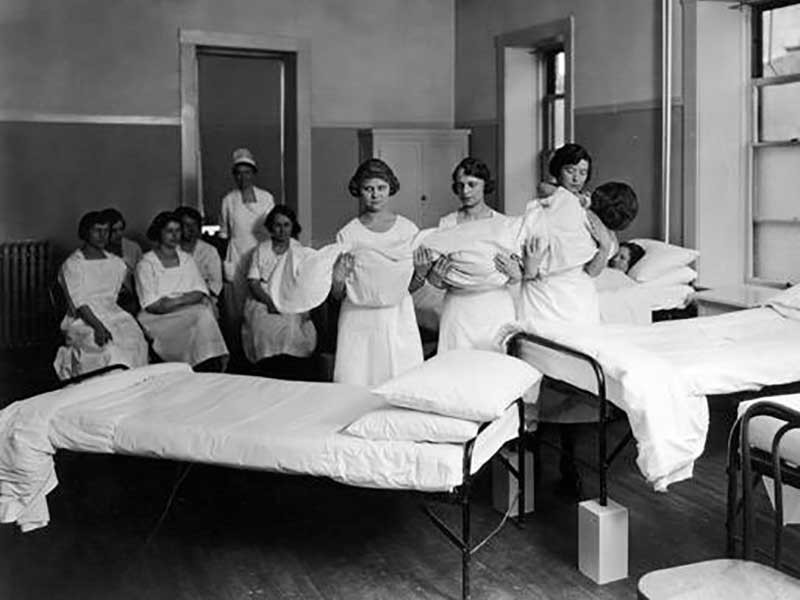 Women lifting another woman for a practice course in nursing at UAC, circa 1923.