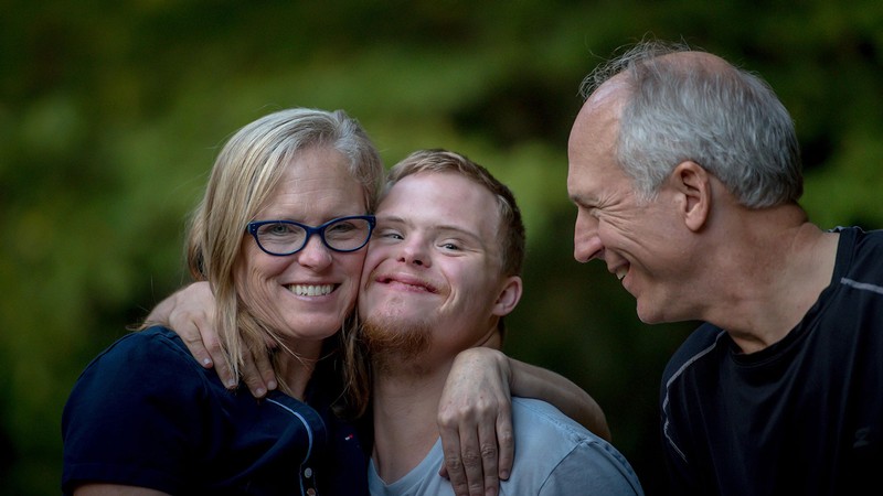 mother and father hugging a son with disabilities.