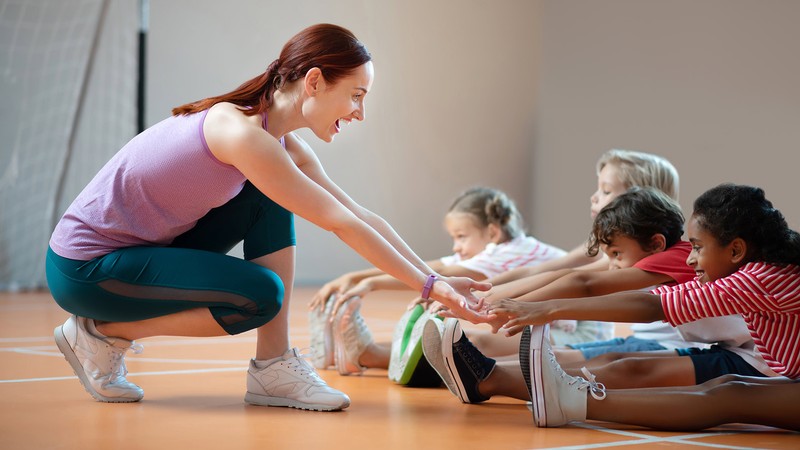 Physical Education teacher helping children stretch.