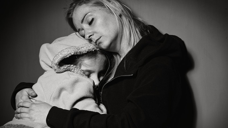 A woman hugs a child.