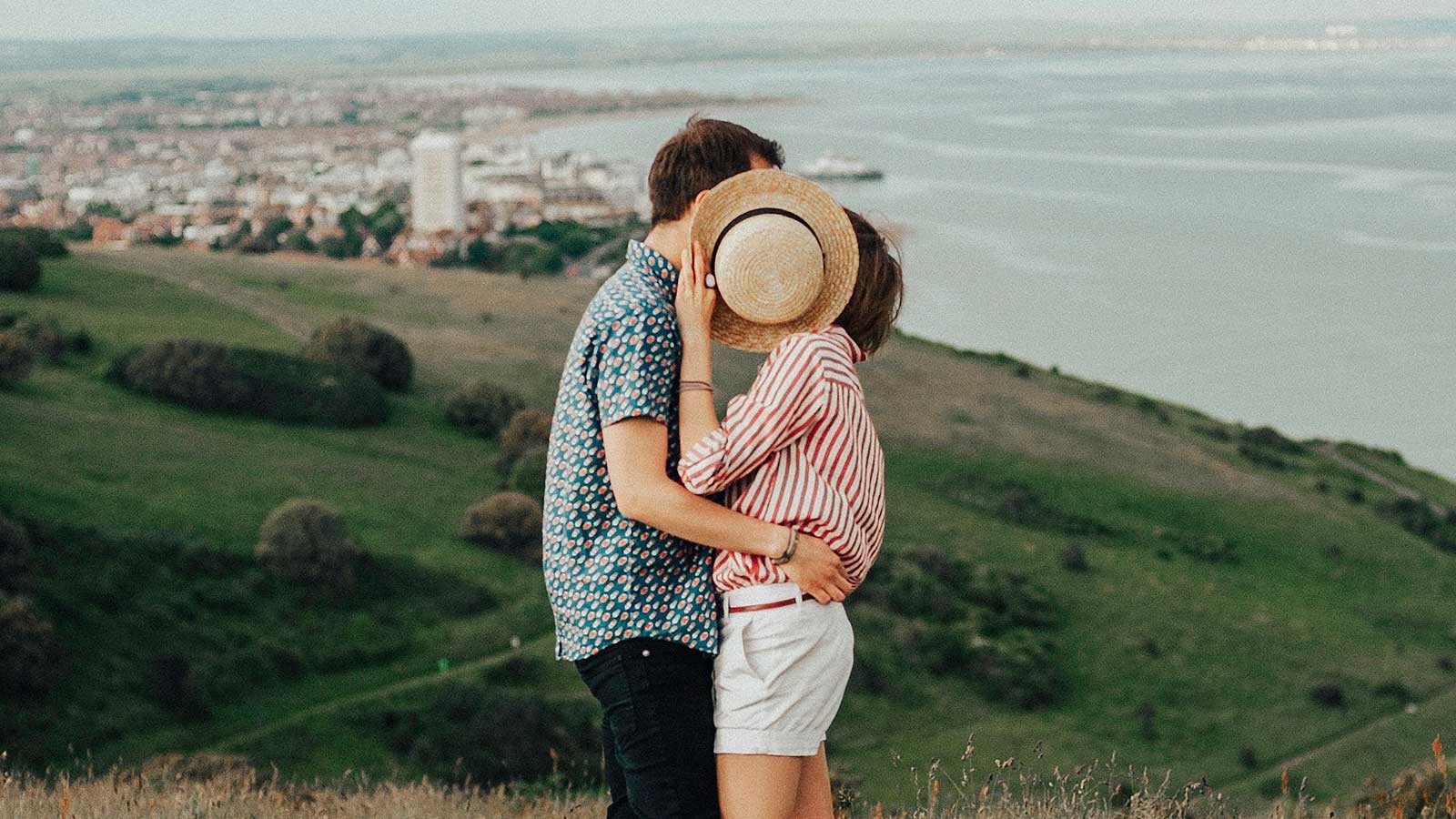 couple kissing in front of a city and coastal skyline.