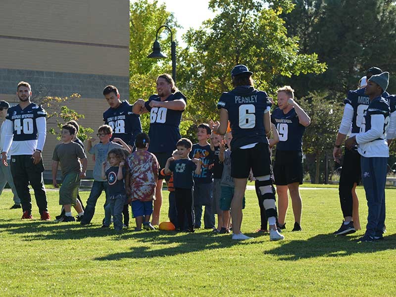 USU Football players playing with Sound Beginnings students