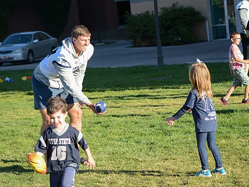USU football players with Sound Beginnings students