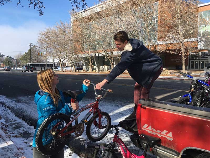 donor handing children's bike to Aggie Blue Bikes