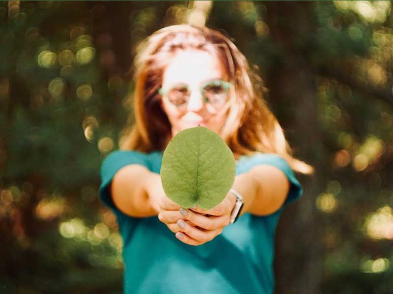 Woman holding a leaf and smiling.