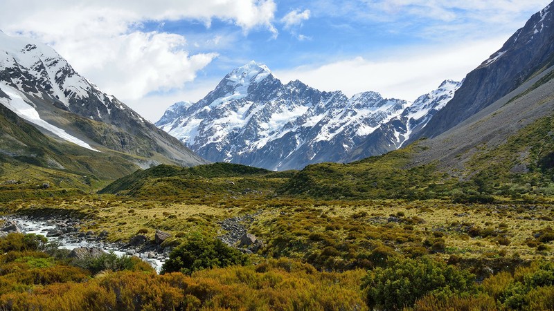 Snow-capped mountains with green valley below.
