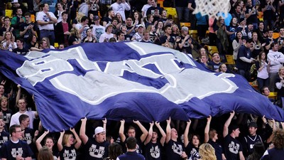 Spectators in the USU Spectrum hold a giant U State flag.