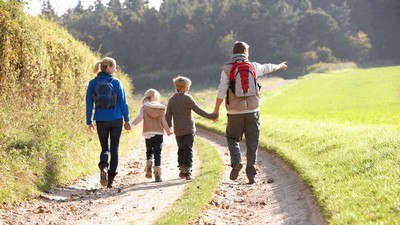 A family hikes along a dirt road.