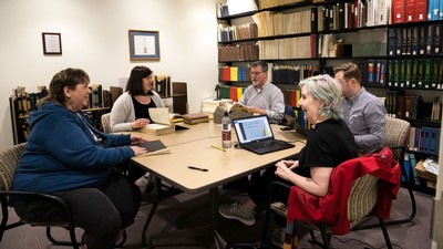 People sit around a table and talk in a library room.