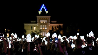 Students hold lanterns shaped like Old Main's tower.