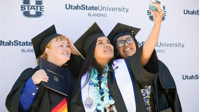 Students pose for a selfie in their caps and gowns.