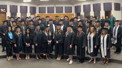 Graduates pose for a photo in their caps and gowns.