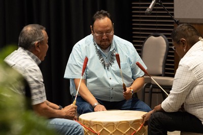 Three men play a drum.
