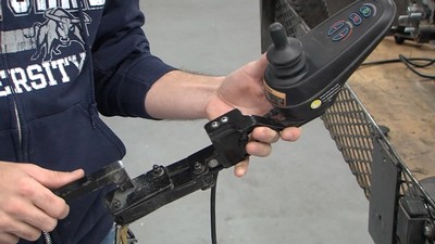 A person holding a wheelchair control.