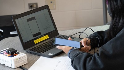 Person plugs a cell phone into a laptop