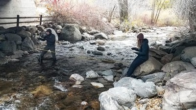 Two people take measurements in a river.