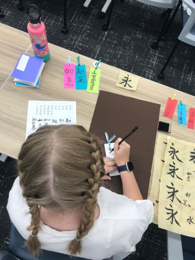 A student practicing writing in Chinese.