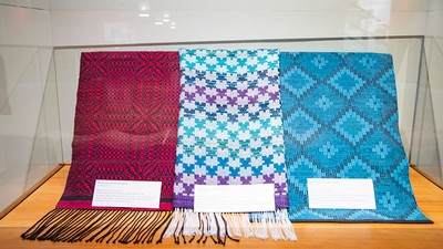 A display case with three separate weavings.