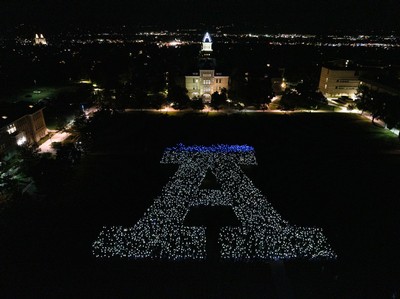 People holding lights form a giant A on the USU Quad as seen from above.