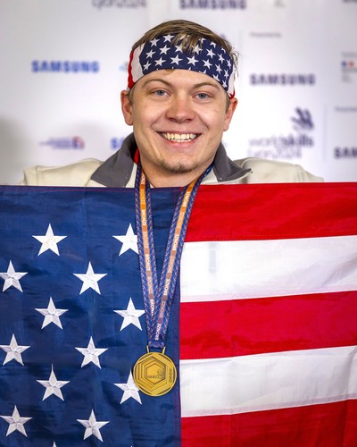 Wyatt Hansen holding an American flag and wearing a bronze medal.