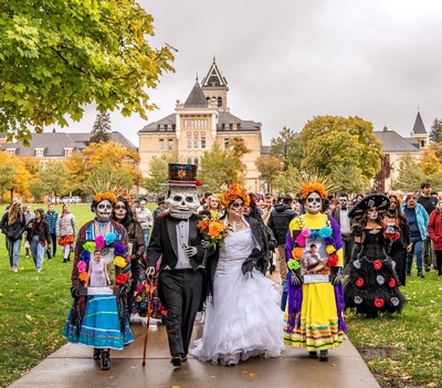 People in costume for Dia de Los Muertos walk across campus.