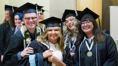 Graduates pose for a photo in their regalia.